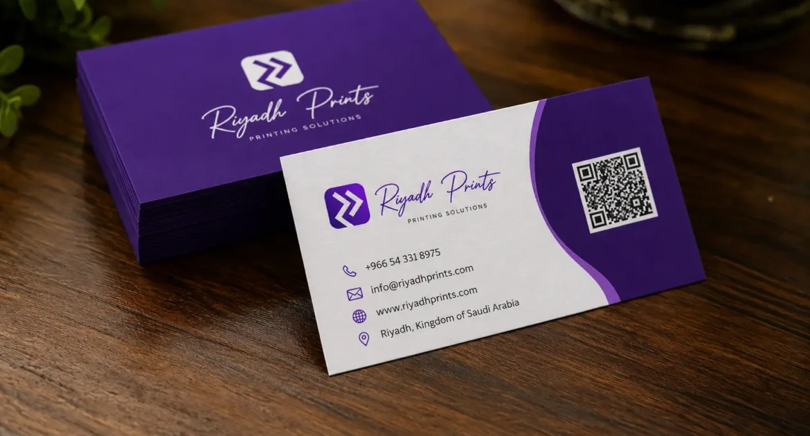 Premium Riyadh Prints business cards displayed on a wooden desk with purple branding and professional print finish.